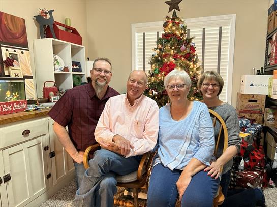 Family members pose together in a warm living room, celebrating the festive season.