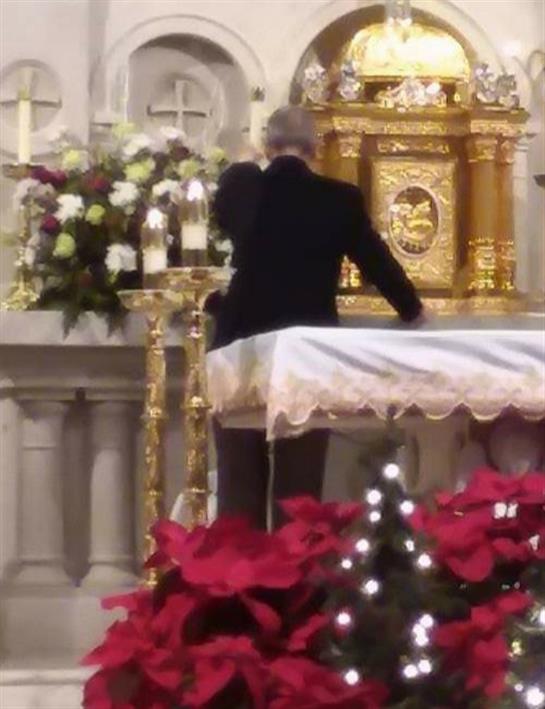 Individual meticulously arranges flowers on a beautifully decorated altar amid a festive atmosphere.