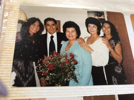 A joyful family poses together indoors, celebrating a special event with flowers in hand.