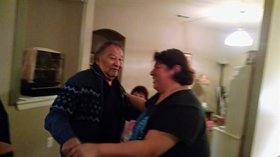 Two people enjoy a lively dance together at a family gathering, surrounded by loved ones.