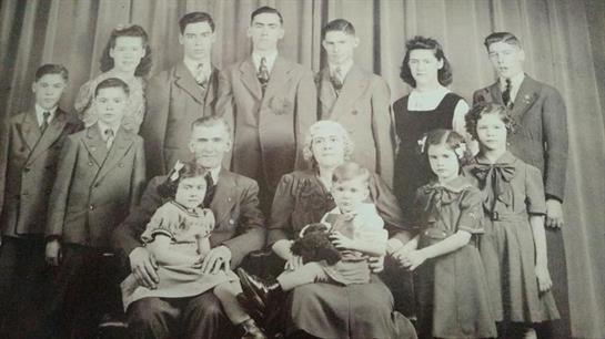 A large family in formal wear poses together, highlighting their bond in a historic setting.