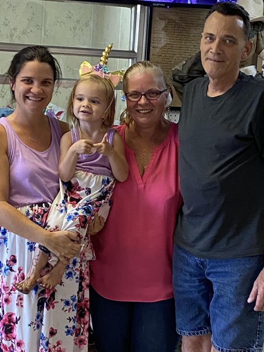 Four family members share smiles and joy in a cozy, warm indoor setting.