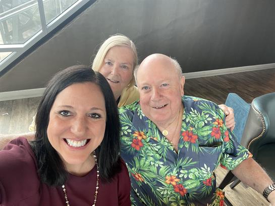 Three friends are smiling and posing closely, showcasing happiness and camaraderie indoors.