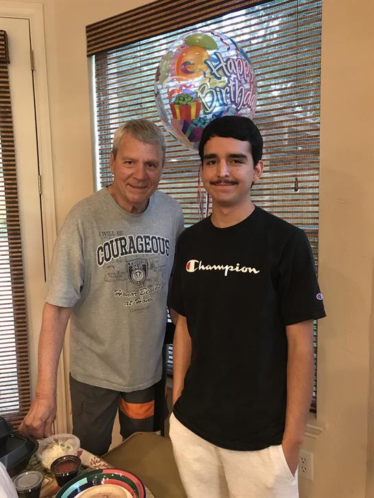 Two family members pose with smiles, celebrating a birthday in a warm, inviting room.