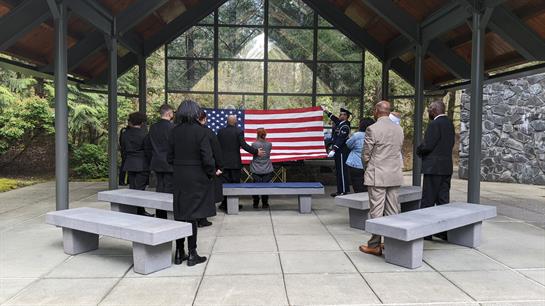 Attendees meet in a serene place to honor a fallen hero and reflect on sacrifices.