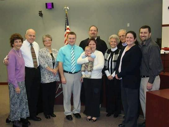 A group of people stands together, celebrating a special occasion in a community center.