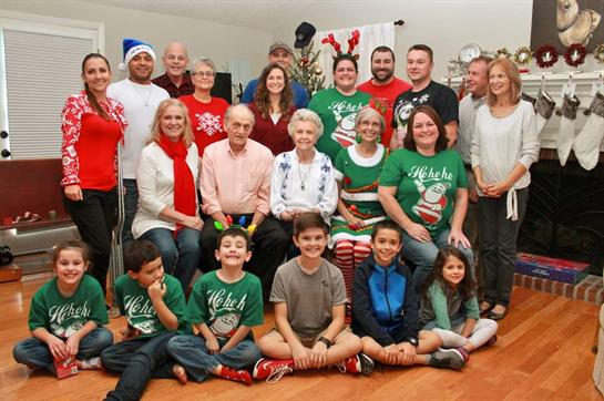 Generations celebrate in cozy home, donning festive outfits and sharing smiles.