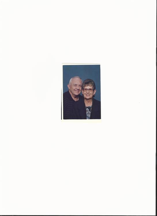 An elderly couple smiles together, showcasing their love and happiness in a cozy environment.