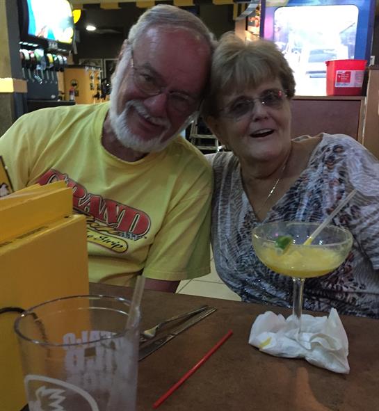 Two seniors happily share a moment together while sipping cocktails at a lively restaurant.