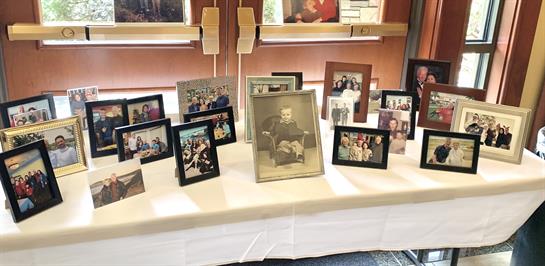 A table is adorned with various family photographs, capturing moments from different generations.