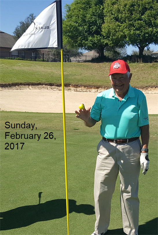 A senior man proudly holds a yellow golf ball near the flag on the course in Texas.