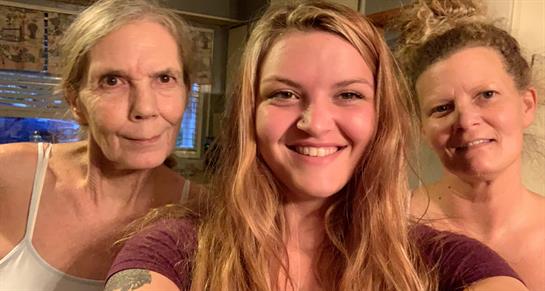 Two women share a joyful moment, smiling at the camera in a warm, inviting indoor space.