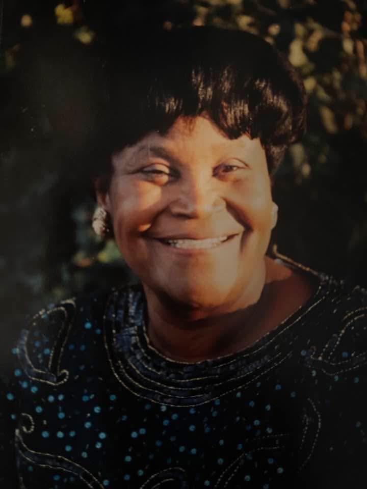 A woman with a bright smile enjoys the outdoors in natural light, radiating happiness and warmth.