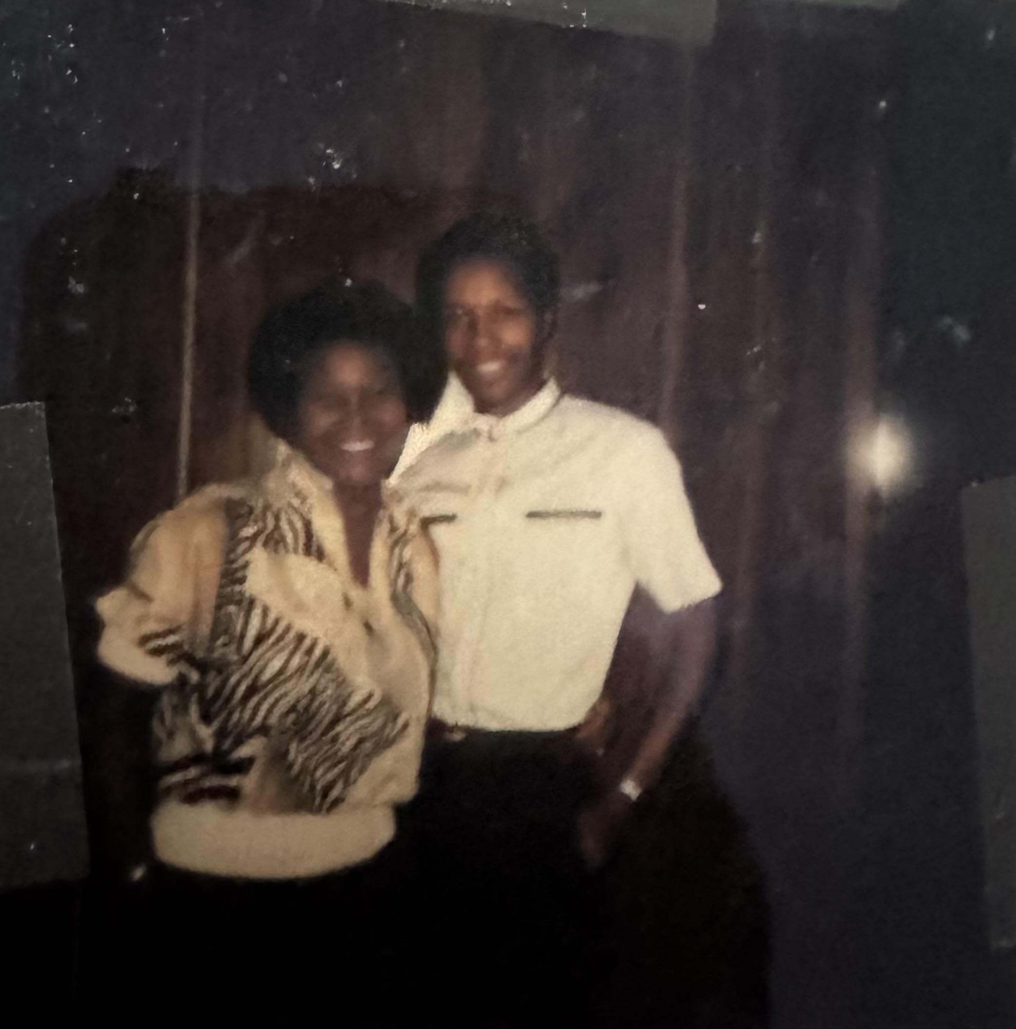 A couple enjoys a joyful moment at a social gathering, dressed elegantly. The ambiance is warm.