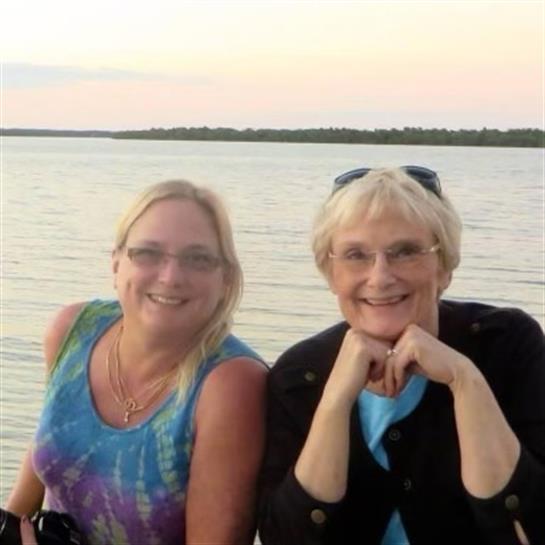 Two women enjoy a peaceful evening by the water, smiling and engaging in conversation.