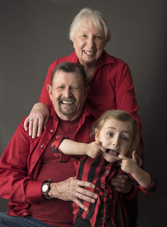 Grandparents share a joyful moment with their grandchild, creating a fun and lively atmosphere.