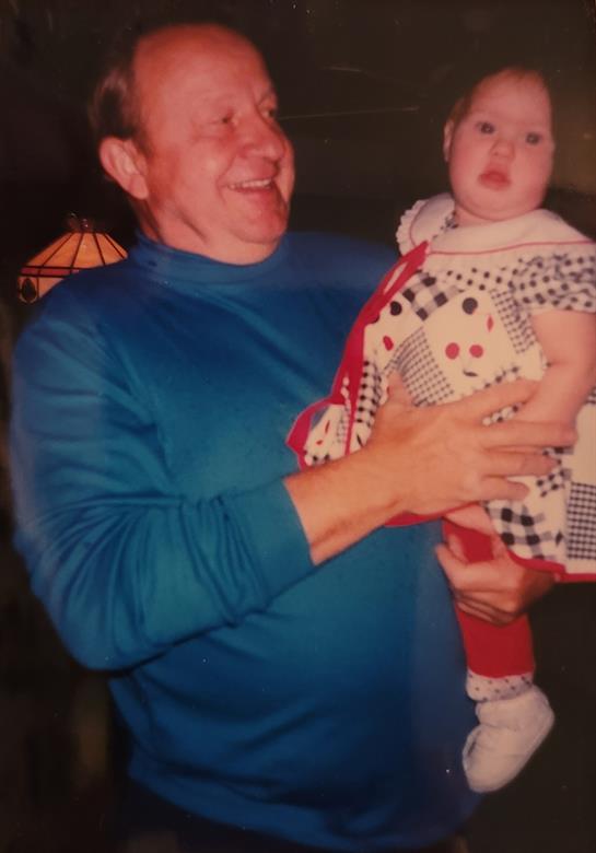 Warm moment captured as a grandfather joyfully holds his smiling granddaughter in a cozy setting.