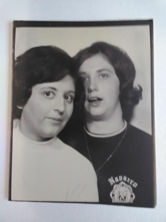 Two friends pose closely together in a playful and nostalgic black and white portrait.