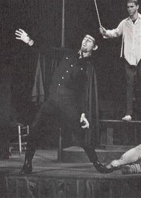 A performer poses dramatically as another supports him on stage, captivating the audience.