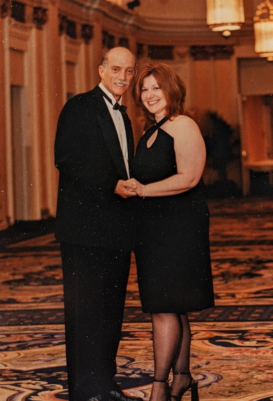 A couple poses together happily in formal wear at a lavish banquet hall celebration.