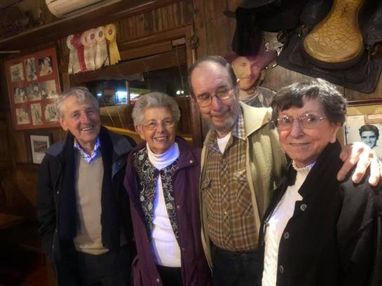 A group of four friends is warmly posing for a cheerful photo in a rustic interior.