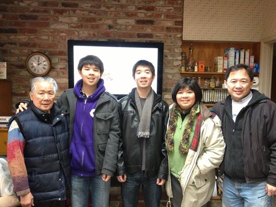 Five family members stand together in a warm living room, sharing joy during a winter evening.