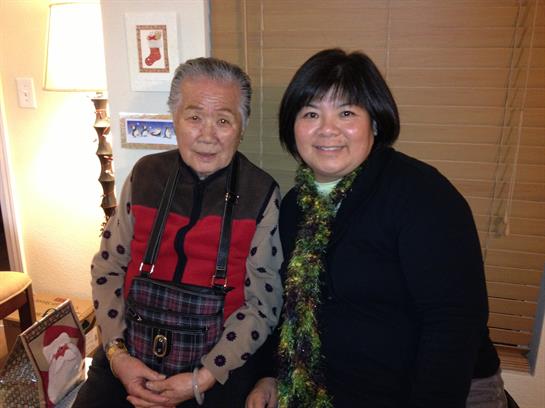 Two women share a warm moment indoors, celebrating together with smiles and cozy attire.