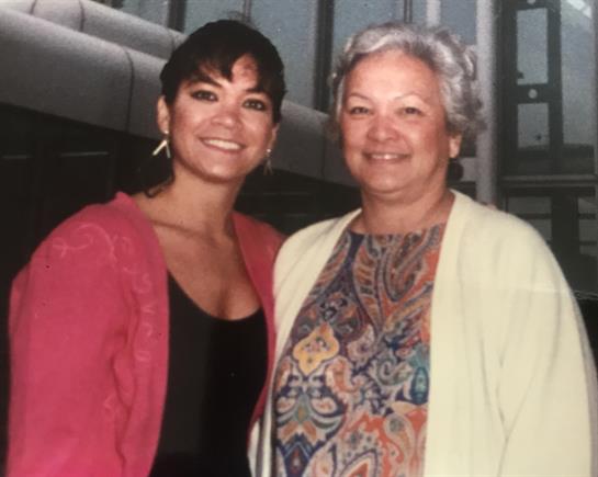 Two women share smiles and warmth while posing together in an indoor location.