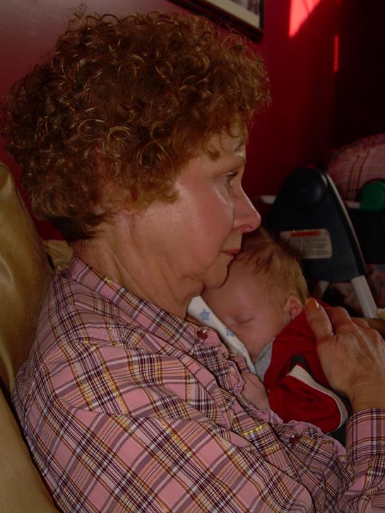 A grandmother lovingly embraces her grandchild, creating a warm family moment in a living room.