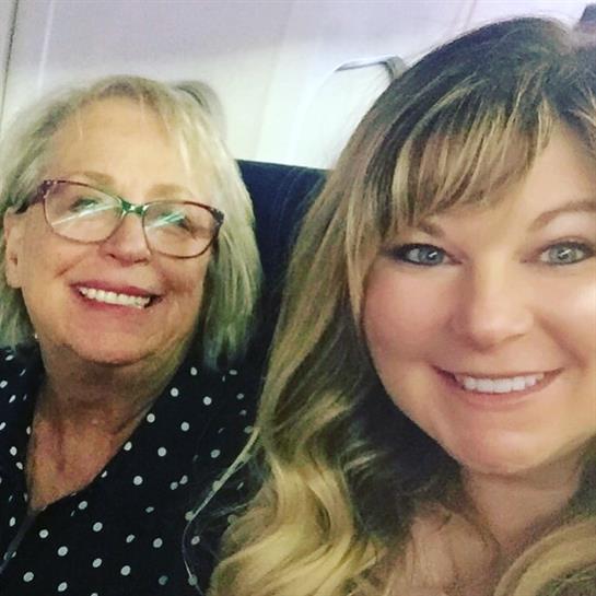Two women are happily taking a selfie together inside an airplane, showcasing their joy.