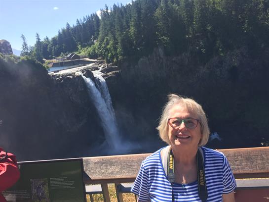 A woman enjoys the view of a stunning waterfall surrounded by trees at a national park.