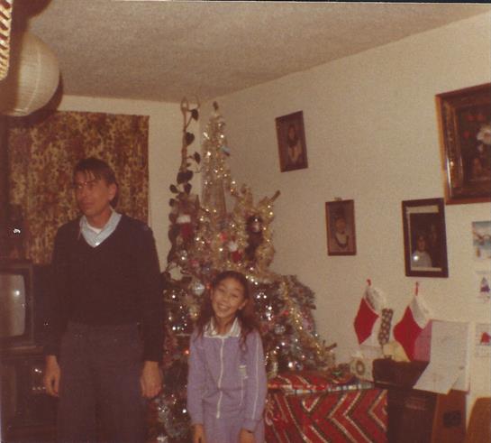 Two children stand by a beautifully adorned Christmas tree filled with ornaments.
