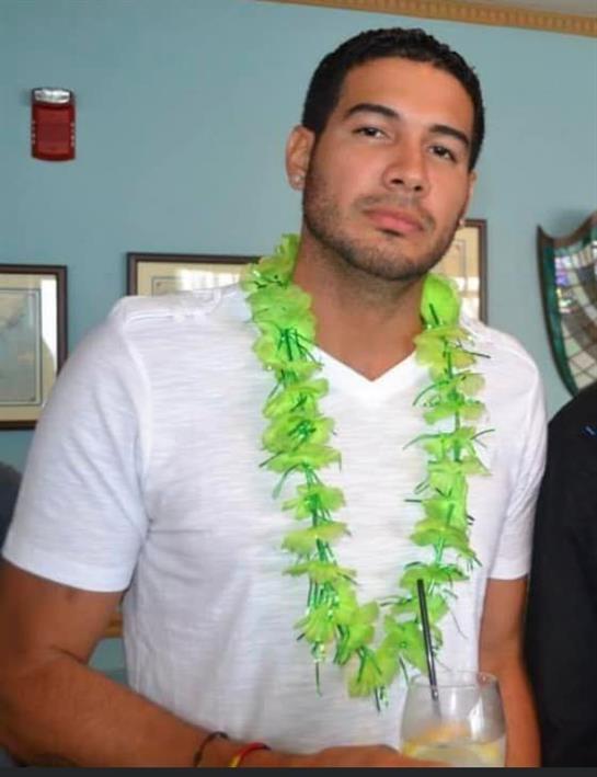 Gathering features a man in a white shirt with a green lei enjoying a drink among friends.