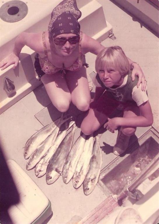 Two people on a boat proudly display a large catch while enjoying a sunny day together.