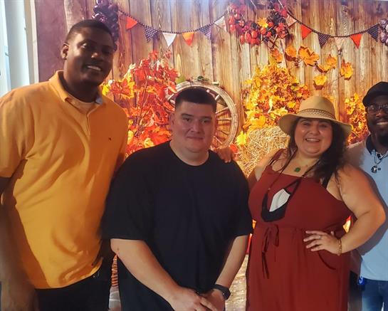 Three friends pose together in a vibrant autumn-themed space filled with decorations and warmth.