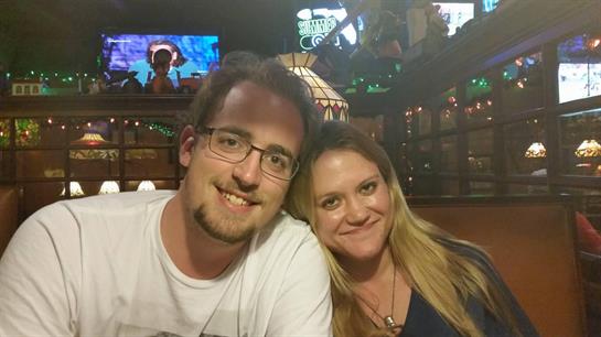 A couple sits together, smiling warmly, enjoying their time in a bustling restaurant atmosphere.