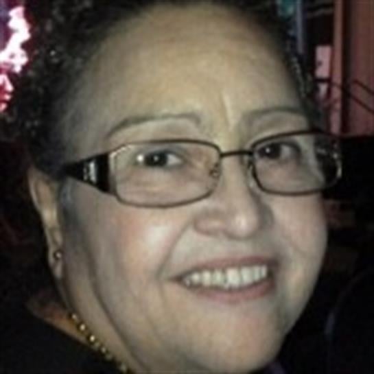 A joyful woman wearing glasses smiles brightly, highlighting a lively atmosphere around her.