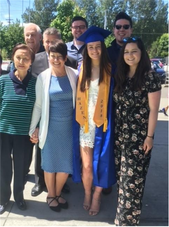 Family members and friends gather outdoors to celebrate a graduation, showcasing smiles and pride.