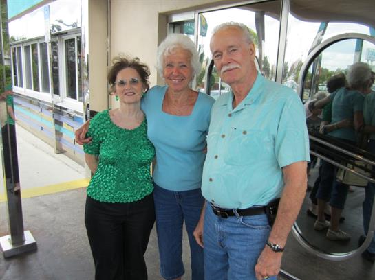 Three friends share laughter and smiles while posing outside a cafe, enjoying their time together.