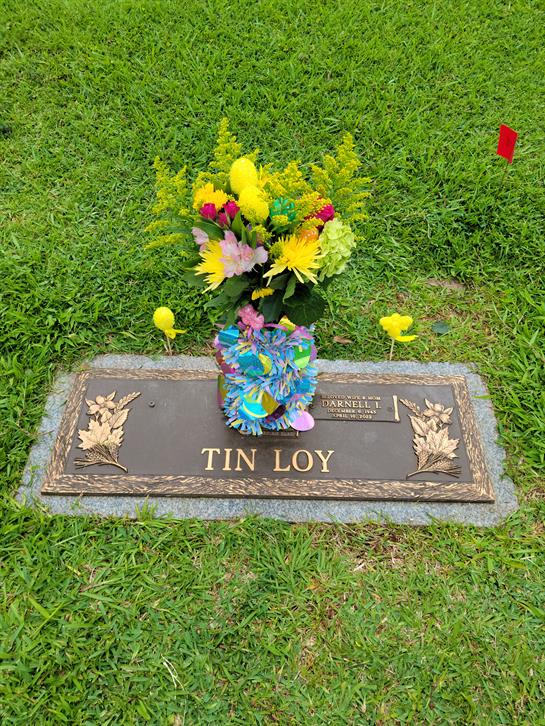 Bright flowers are arranged on a gravestone, creating a vibrant tribute in a peaceful cemetery.