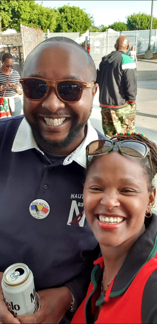 Two smiling individuals pose together at a lively event in the city.