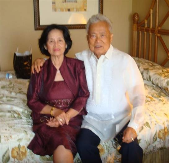A couple shares a tender moment on a bed, enjoying each other’s company in a warm atmosphere.