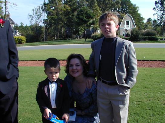 Family celebrates together in a lush green park with children dressed in formal wear and smiles.