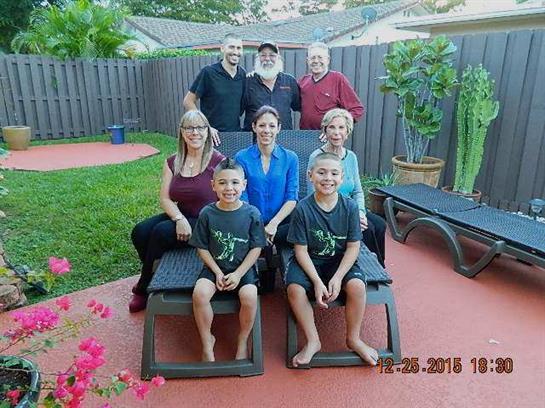 Group of family members relaxing outdoors in a backyard, enjoying quality time together in the sun.