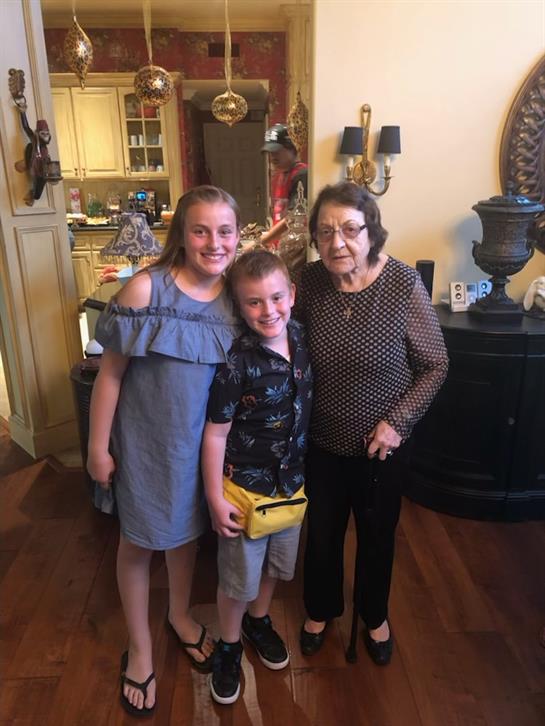 Two children enjoy a joyful moment with their grandmother in a warmly decorated home.