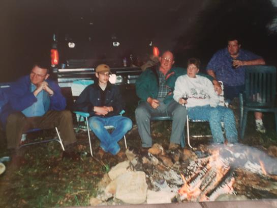 Group of friends enjoying a night by the campfire, sharing stories and drinks under the night sky.
