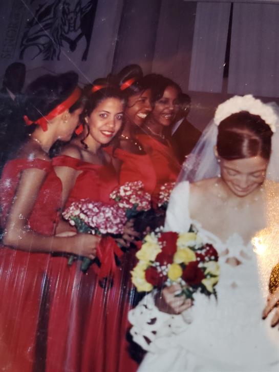 Joyful gathering of bridesmaids in red dresses alongside the bride holding a vibrant bouquet.