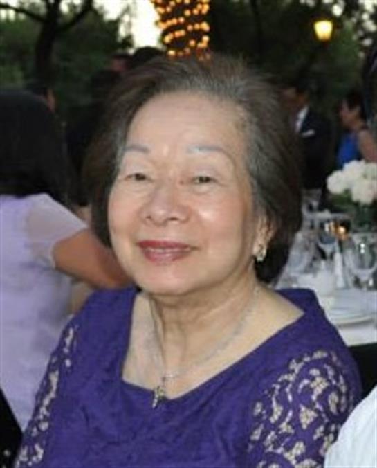 A senior woman in purple enjoys a joyful gathering full of celebration.