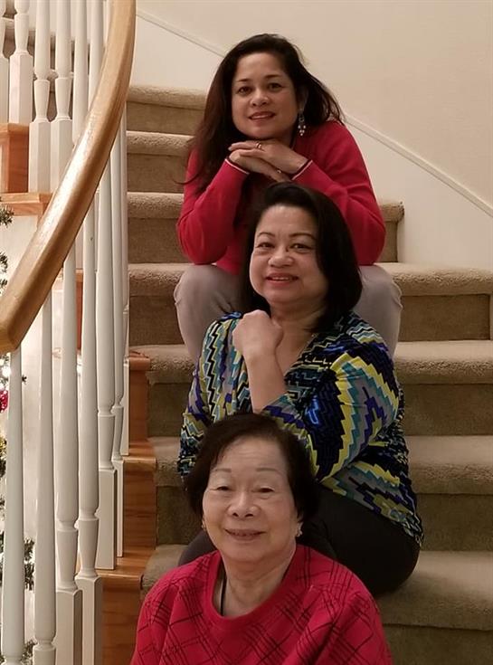 Three women enjoying quality time together on staircase, dressed comfortably and smiling.