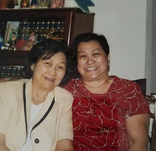 Two women share joyful smiles while sitting closely in a warm and inviting living room.